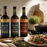 Three bottles of Rio Vista 'Nothin' But Olives' extra virgin olive oil in different flavours displayed on a rustic kitchen counter next to a prepared pasta dish, with a stove and tiled background.