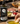 Bottle of Elisi Kalamata EVOO with a person dipping bread into olive oil on a table with food.
